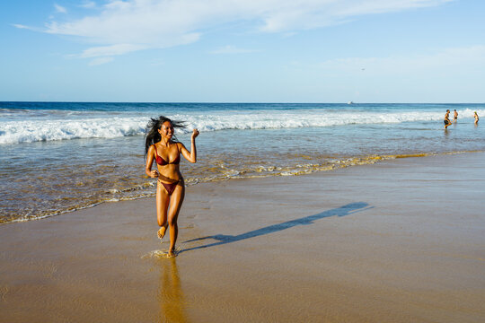 Asian woman in a bikini running along the beach, Fernando de Noronha, Pernambuco, Brazil
