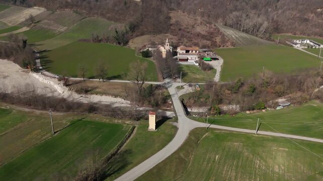 Riverbed maintenance along the Chiavenna stream in Val Chiavenna near Lugagnano Val d'Arda, Piacenza, Emilia-Romagna, Italy, with flood mitigation earthworks beside the historic church, drone oblique