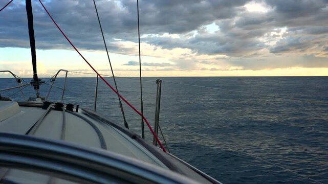 serene sailboat stationary on the ocean with wooden deck and metal masts under a cloudy sky during a peaceful vacation adventure in travel and natural beauty setting.