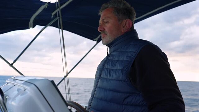 man steering boat in serene ocean with cloudy sky, navigating with focused side view of wooden oars and metal parts, travel adventure outdoor scene with blue and white tones.
