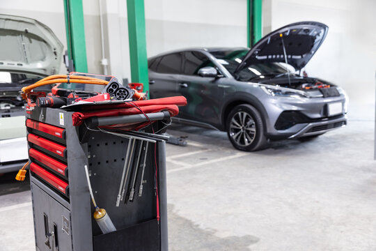Professional service tool cart with insulated tools and high-voltage electrical connectors in a modern electric vehicle repair workshop.