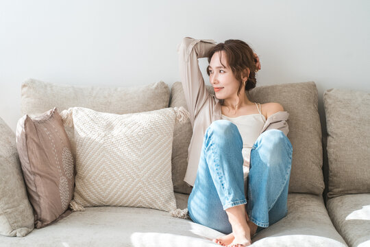 A stylish Asian housewife relaxing on the living room sofa.