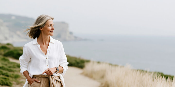 Womens health menopause middle aged woman walking coastal trail smiling in breeze