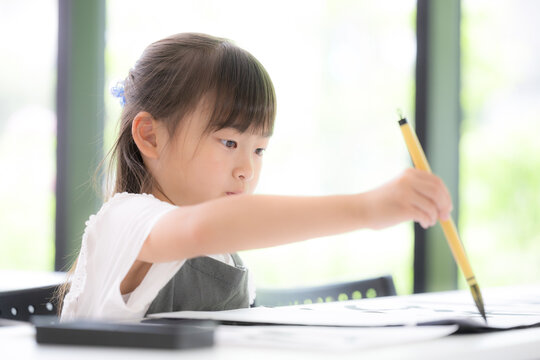 書道に集中して筆で文字を書く小学生の女の子・習字を学ぶ日本の子ども