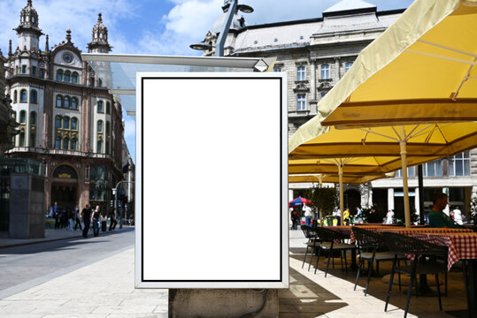 white blank advertising billboard. street mockup panel. digital lightbox poster ad banner board. bus shelter advertising. european urban scene background. vertical format sign. stucco facades