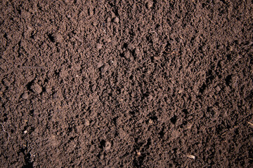 Soil texture fills fertile ground. Brown soil covers garden surface. Topsoil forms earthy background. Soil closeup highlights seedbed texture. © Svitlana