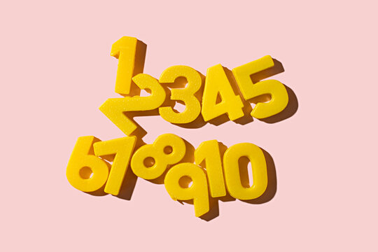 counting with vintage yellow numbers 1 through 10 scattered on a pink background with shadows