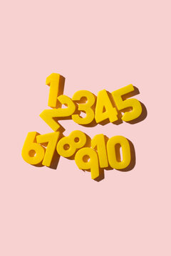 counting with vintage yellow numbers 1 through 10 scattered on a pink background with shadows