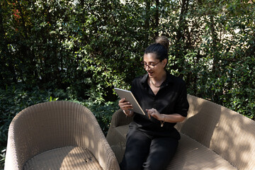 Obraz premium Horizontal view of a female freelancer staying connected online with her digital tablet while relaxing in nature.