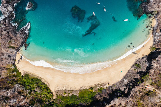 Aerial view of Baia do Sancho with boats in the turquoise cove, Fernando de Noronha, Pernambuco, Brazil