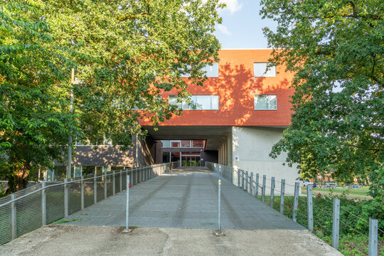 Hasselt, Belgium. Modern university campus entrance with elevated building, pedestrian bridge and surrounding trees