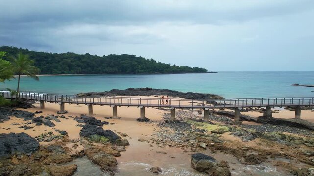 Aeria circular view of a European couple walking on the bridge connecting the Bom Bom beach to the islet of the same name.Prince Islan,Africa