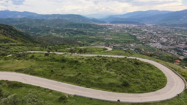 Drone view of a cyclist riding a winding mountain road above Elbasan.