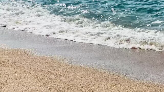 Slow motion wave foam washing onto sandy beach
