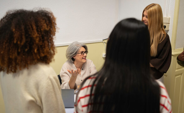 Experienced woman mentoring young diverse women during a business or educational meeting