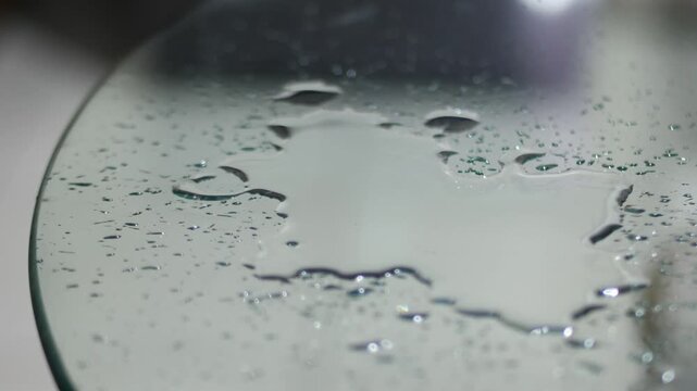 Water Droplets Splashing on Glass Table Surface in Close Up