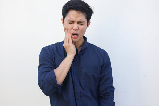 close up young asian man frown and use hand to massage on cheek after feeling pain or hurt from tmj muscle symptom at home for un healthy lifestyle and treatment concept