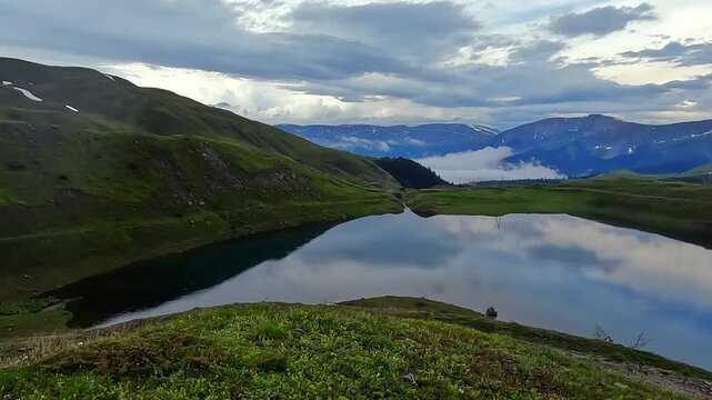 Camera overlooking Karagoli Lake wide shot in Georgia, showing alpine water, green highlands, distant ridges, and travel destination context for tourism, nature, and mountain landscape footage
