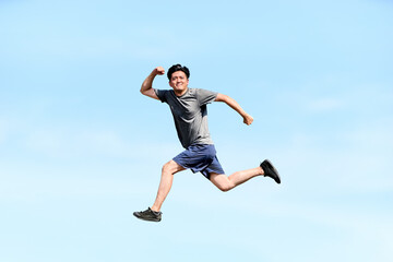 Obraz premium 青空を背景に笑顔で高くジャンプしガッツポーズで希望や未来や成功をイメージするアクティブな男性