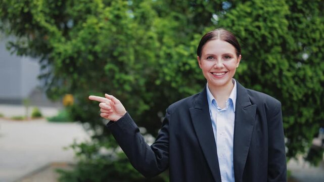 Smiling business professional points towards new possibilities. Expresses happiness, offering clear direction. Positive outlook and guidance. Ideal for themes of opportunity, leadership, and success.