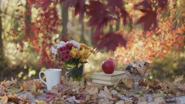 Autumn table with apple and books. Cozy outdoor fall moment. Autumn leaves framing table. Warm seasonal table setup. Cozy fall afternoon table.