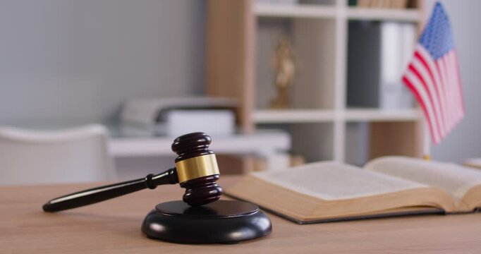 Courtroom with chairmans gavel, the USA flag and law book. Judge workplace. Slow motion video. US Law, juctice, legislation and judgemenet concept. No people. Law enforcement office. 
