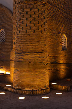 Massive brick column and walls of Ichan Kala illuminated at night in Khiva, Uzbekistan. Warm uplighting highlights ancient brickwork and lattice windows, ideal for travel and heritage publication.
