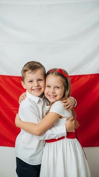 Happy Polish children boy and girl hugging in front of national flag celebrating independence day or national holiday concept