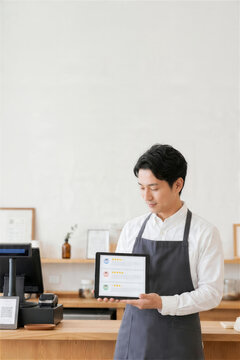 レビュー管理画面をタブレットで見せる日本人男性スタッフ