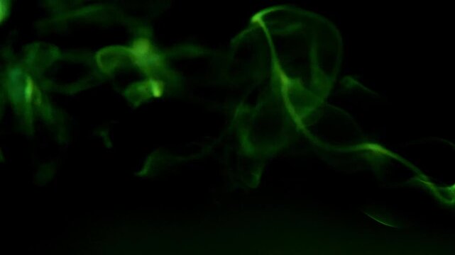 Green smoke wafting in the darkness, creating an ethereal and mysterious atmosphere. The wisps of smoke dance and swirl, forming delicate patterns against the black void