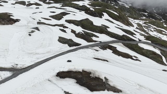Kitzsteinhorn, Austria - June 09 2026: Cinematic 4K drone footage tracking a snowmobile as it rides across the snowy ski slopes of Kitzsteinhorn Glacier in Kaprun, Austria. Spectacular aerial views sh