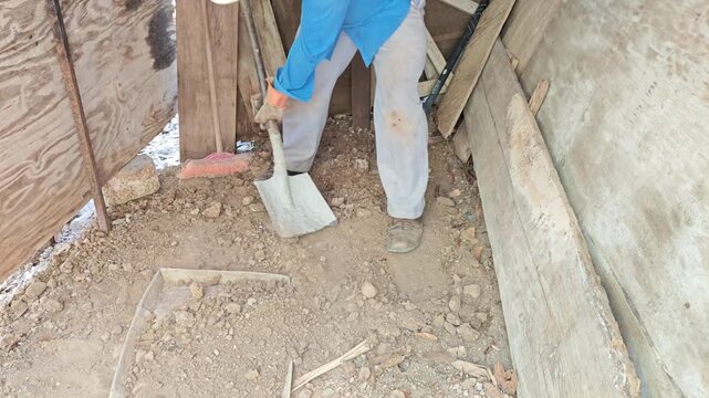 Worker shoveling soil into aluminum tray and lifting it