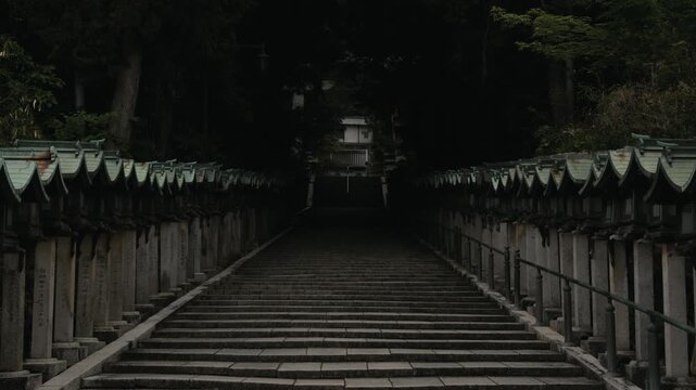 Moody stone staircase at Hozanji Temple in Ikoma, Japan, lined with traditional lanterns and surrounded by trees in a quiet sacred setting.