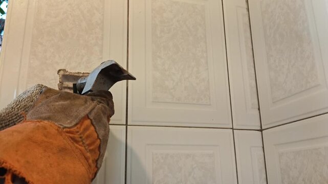 Construction worker using hammer to drive anchor pin into wall base