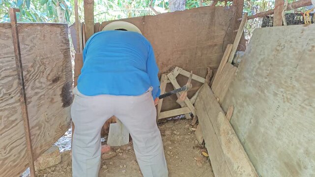 Young man loosening hard soil ground using heavy pickaxe tool