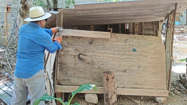 Young man hammering metal nail into plywood sheet board
