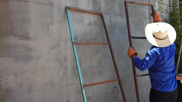 Worker cleaning rusty metal profiles using chemical paint thinner solvent