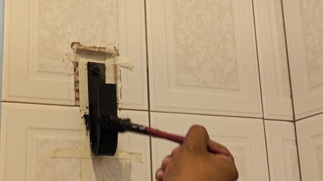 Hand carefully painting metallic flat bar base inside bathroom interior