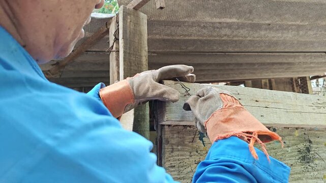 Mans hands arranging binding wire to tie wooden structure parts