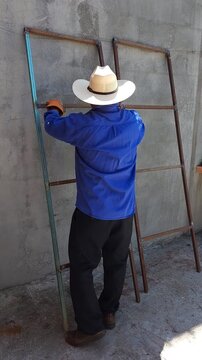 Worker vigorously brushing rusty iron profiles with wire brush tool