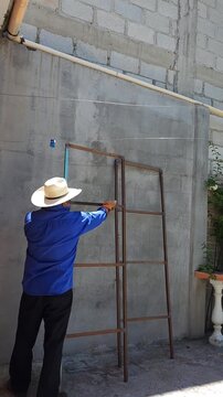 Person rubbing rusty iron bar with industrial cotton waste and thinner