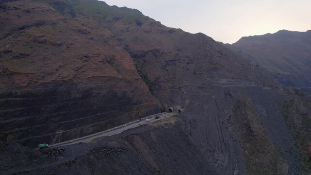 Vehicles approach twin tunnels on the Swat Motorway M16 through steep rocky mountains, Khyber Pakhtunkhwa, Pakistan