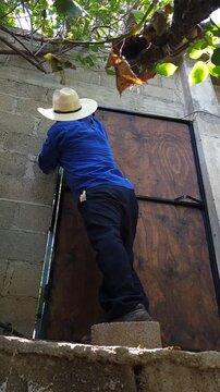 Painter coating metal profile borders on wooden door with brush