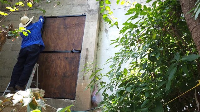 Person renovating outdoor garden metal gate using paintbrush and paint