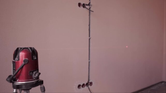 Self leveling laser level in room during installation of new electrical wiring and wall preparation for finishing work phase