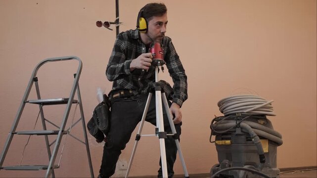 Professional uses laser level for precise marking of lines for future electrical installation work in construction site interior