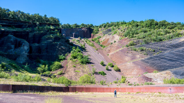 Croscat volcano quarry in La Garrotxa, Catalonia, Spain. Visitor standing below colorful volcanic scoria layers inside the exposed cone near Olot.