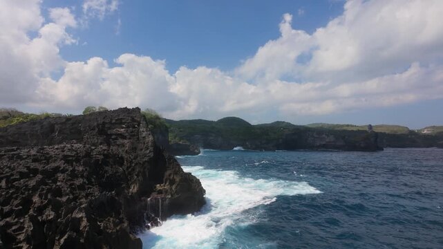 Huge wave crashing upon the rocks near angel's billabong in nusa penida, bali. Slow motion shot of white foamy turquoise blue ocean water on nusa penida island. 
