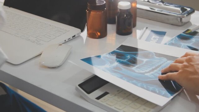 Medical professionals working together at an office desk, discussing information on a laptop, a male doctor pointing at the screen while holding a digital tablet