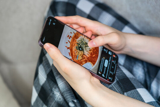 Teenage girl sitting on a sofa and browsing social media comments section on her smartphone. Concept: youth screen time and phone addiction risks